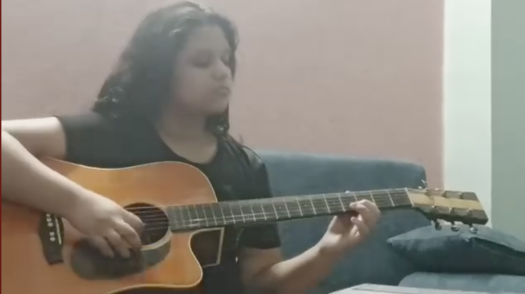 Ishi performing instrumental music on guitar as part of a musician duo.