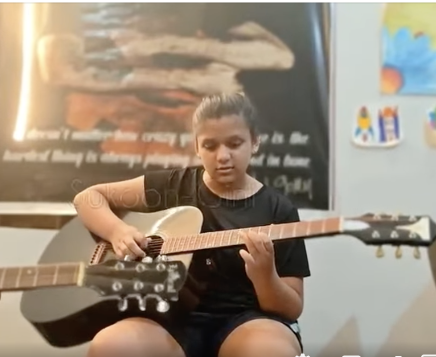 Ishi practicing acoustic guitar during RSL Grade 1 exam preparation – young musician focused on learning chords and strumming techniques.