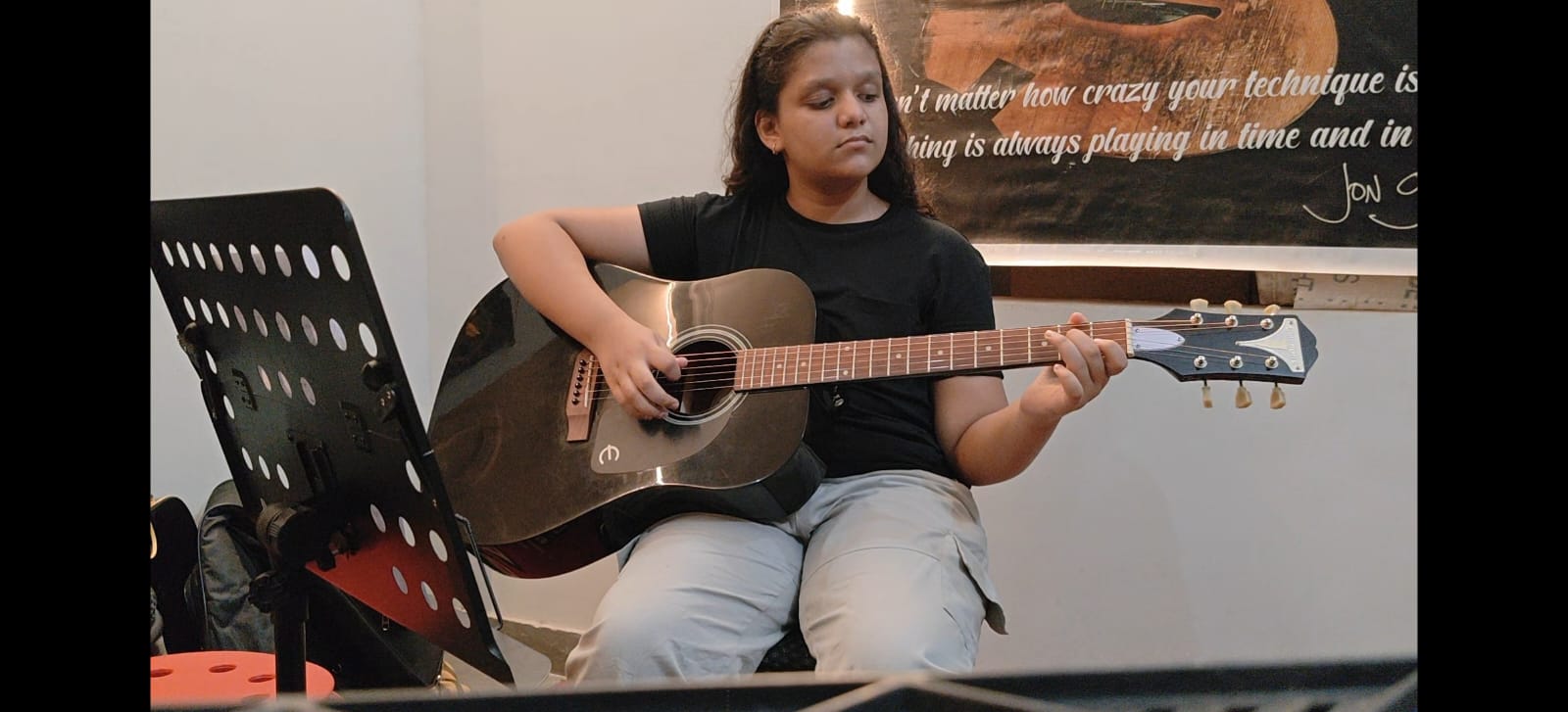 Close-up of Ishi playing guitar, showcasing dedication as a student guitarist preparing for Rockschool music exams.