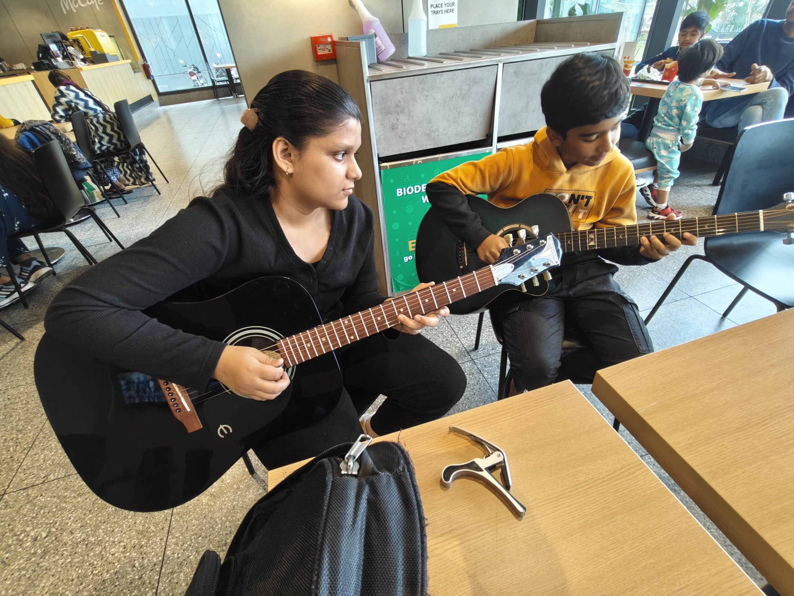 Ishi and friends jamming on guitars in a McDonald’s cafe