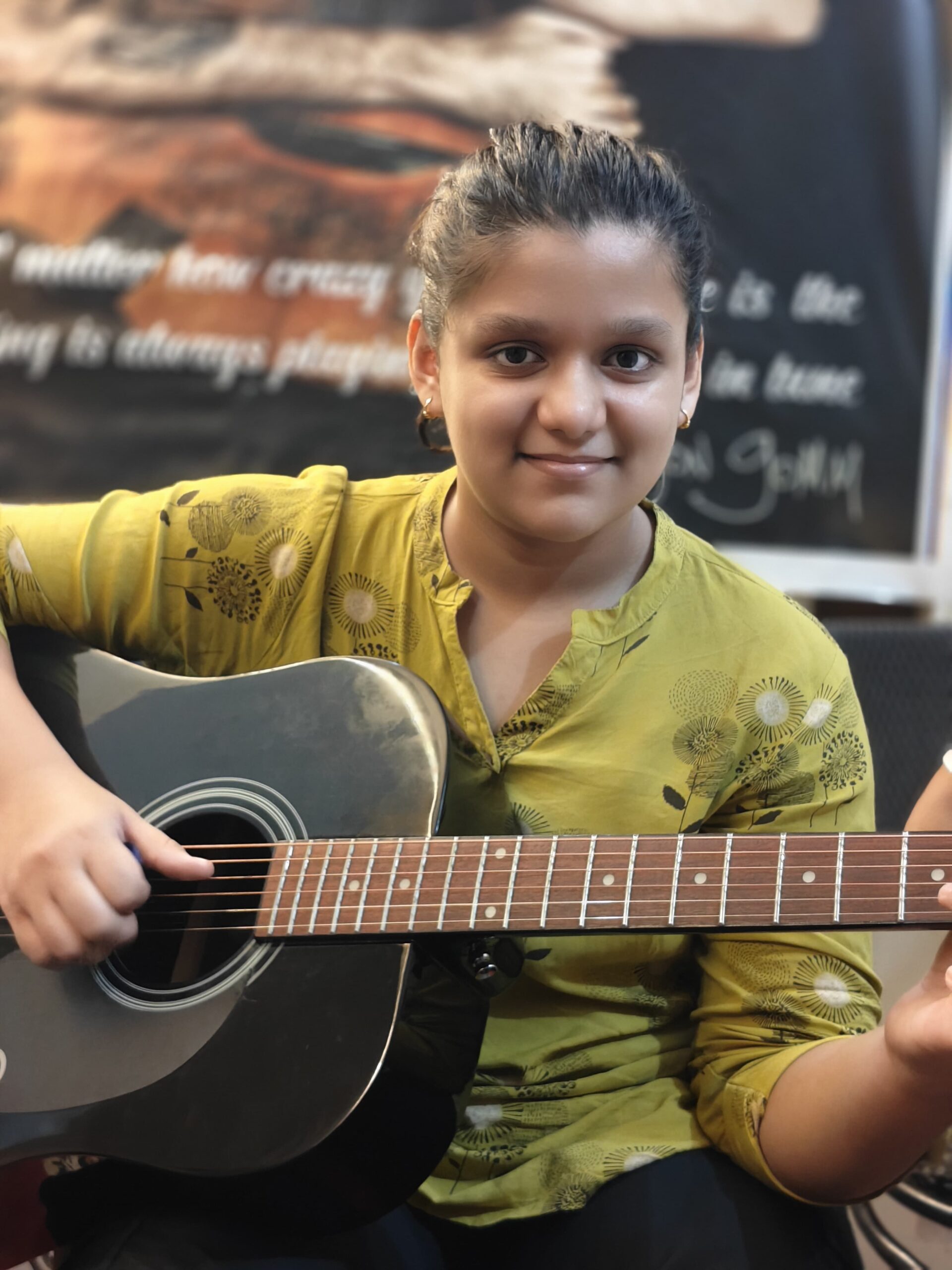 Young guitarist Ishi Garg playing an acoustic guitar indoors during practice.
