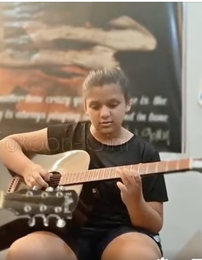 Ishi practicing acoustic guitar during RSL Grade 1 exam preparation – young musician focused on learning chords and strumming techniques.