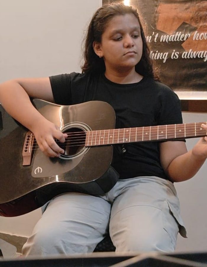 Close-up of Ishi playing guitar, showcasing dedication as a student guitarist preparing for Rockschool music exams.